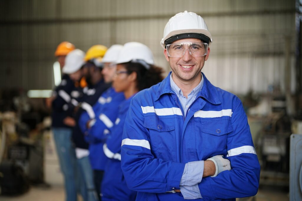 Young confident leader of team standing in front of factory workers